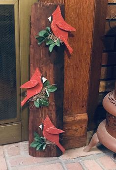 three red birds sitting on top of a piece of wood next to a fire place