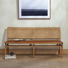 a wooden bench sitting next to a book on top of a hard wood floor near a wall