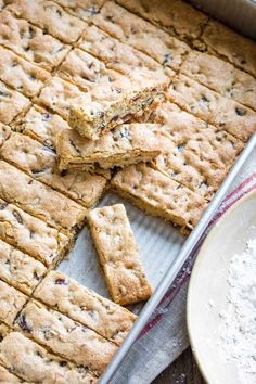 a baking pan filled with cookies next to a bowl of oatmeal