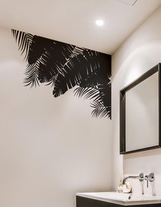 a bathroom with black and white palm leaves painted on the wall next to the sink