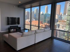 a living room filled with furniture and large windows overlooking the cityscape in the distance