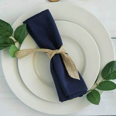 a place setting with blue napkins and green leaves