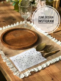 a wooden table with white doily on it and gold utensils in the middle