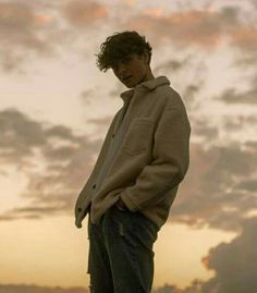 a man standing on top of a skateboard in front of a cloudy blue sky