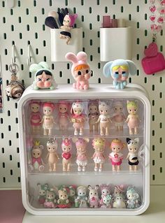 there are many little dolls on the shelf in this toy display case that is filled with them