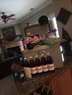 a cooler filled with drinks on top of a kitchen counter next to a ceiling fan