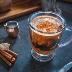 a glass mug filled with liquid and cinnamon sticks