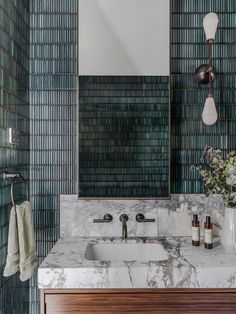 a bathroom with marble counter tops and green tiles on the walls, along with a wooden cabinet