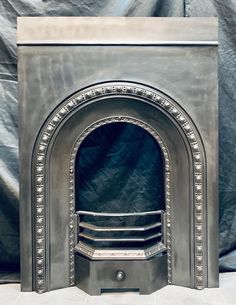 an old fireplace with a metal frame and decorative designs on the front, sitting against a black backdrop