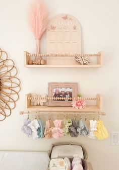 there are two shelves above the baby crib with clothes hanging on it and a pink flower