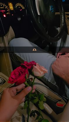 a man is holding a rose in his hand while sitting in the driver's seat