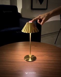 a person is lighting a lamp on a table with a chair in the back ground