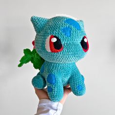 a hand holding a crocheted blue stuffed animal