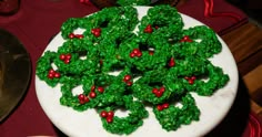 a white plate topped with green and red christmas wreath cookies on top of a table