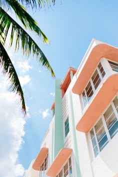 an orange and white building with palm trees in the foreground