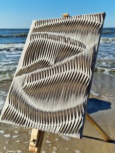 an easel sitting on top of a sandy beach next to the ocean with waves coming in