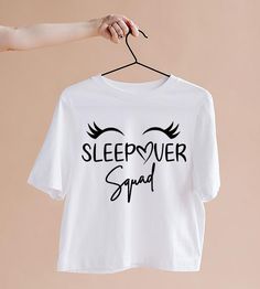 a white t - shirt with the words sleepover squad printed on it hanging from a clothes line