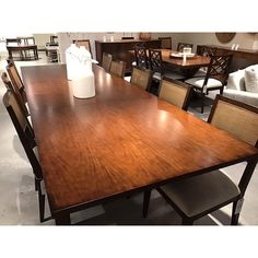 a large wooden table with chairs around it in a room filled with other tables and chairs