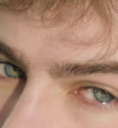 a close up of a man's face with brown hair and blue eyes looking at the camera