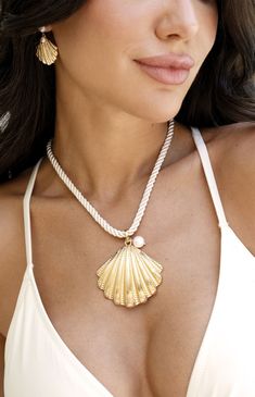 Online only! Make a bold statement with Ettika's Scallop Shell Pendant Necklace, showcasing a chunky white chain and a large seashell pendant adorned with a faux pearl. The gold finish adds a touch of luxury, perfect for any beach-inspired look.


	18k Gold Plated, Zinc, Silk Cord, Freshwater Pearl
	16" with 3" extender
	2" Scallop Shell Pendant
	Lobster Clasp Gold Shell Necklace With Pearl Chain For Beach, Earrings Outfit, Scallop Shell, Back Necklace, Scallop Shells, Silk Cord, Accessories Ideas, Pearl Charms, Shell Earrings