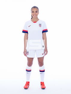 a female soccer player poses for the camera in her white uniform and red shoes,