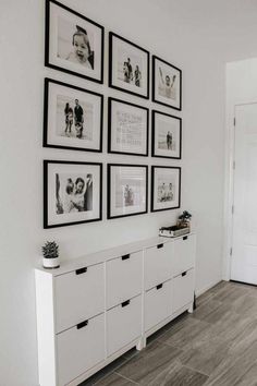 a white room with pictures on the wall and drawers in front of an open door