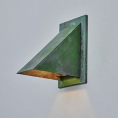 a green wall light mounted to the side of a white wall