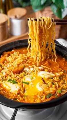 noodles being lifted from a skillet with chopsticks