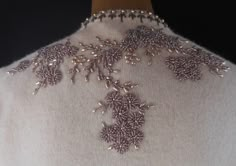 the back of a woman's sweater with beading on it