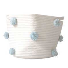 a large white basket with blue pom poms on the handles and bottom half