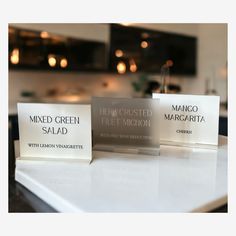 three glass business cards sitting on top of a white counter next to a kitchen sink