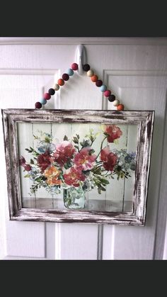 a vase with flowers is hanging on the door frame and beaded necklaces are attached to it