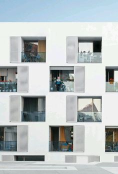 people are standing in the windows of an apartment building that has balconies on each floor