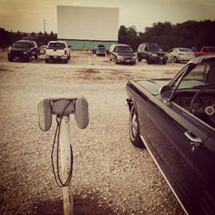 a parking lot with cars and a movie screen in the background