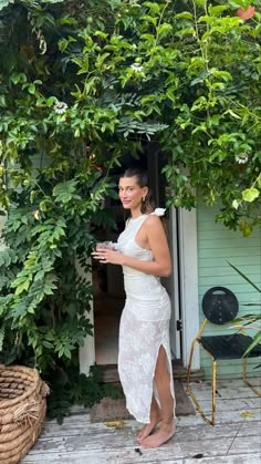 a woman in a white dress is standing outside