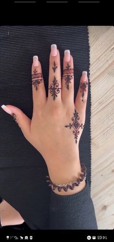 a woman's hand with hennap and cross tattoos on her left hand