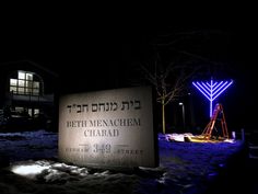 a lit up sign in front of a building at night with snow on the ground