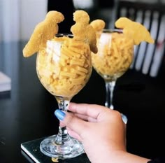 two glasses filled with macaroni and cheese sitting on top of a black table