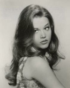 an old black and white photo of a woman with long hair wearing a halter top