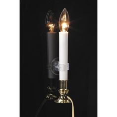 two white candles are lit on a black stand with a light bulb attached to it