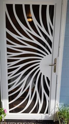 a white door with black and white designs on the glass, in front of a blue house