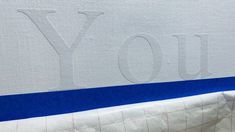 the back side of a mattress with blue and white lines on it that says you