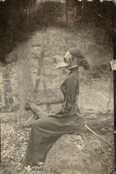 an old photo of a woman sitting on a rock with a bird's beak in her mouth