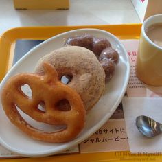 a plate with some doughnuts on it next to a cup of coffee