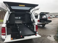 the back end of a white van parked in a parking lot next to other vehicles