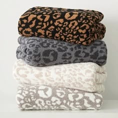 five towels stacked on top of each other in different colors and patterns, all with leopard print