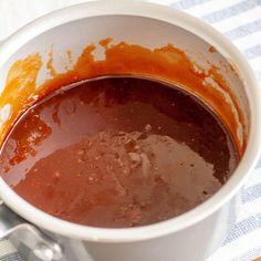 a white cup filled with sauce sitting on top of a table