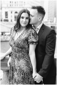 a man and woman standing next to each other in front of a body of water