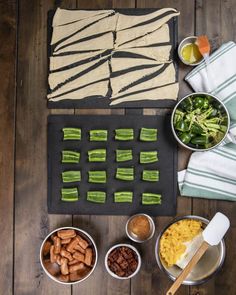 an assortment of food is laid out on a wooden table with utensils and napkins