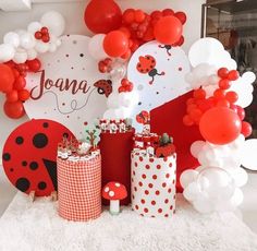 a table topped with lots of red and white balloons covered in ladybug decorations